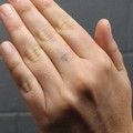 Cross tattoo on left middle finger